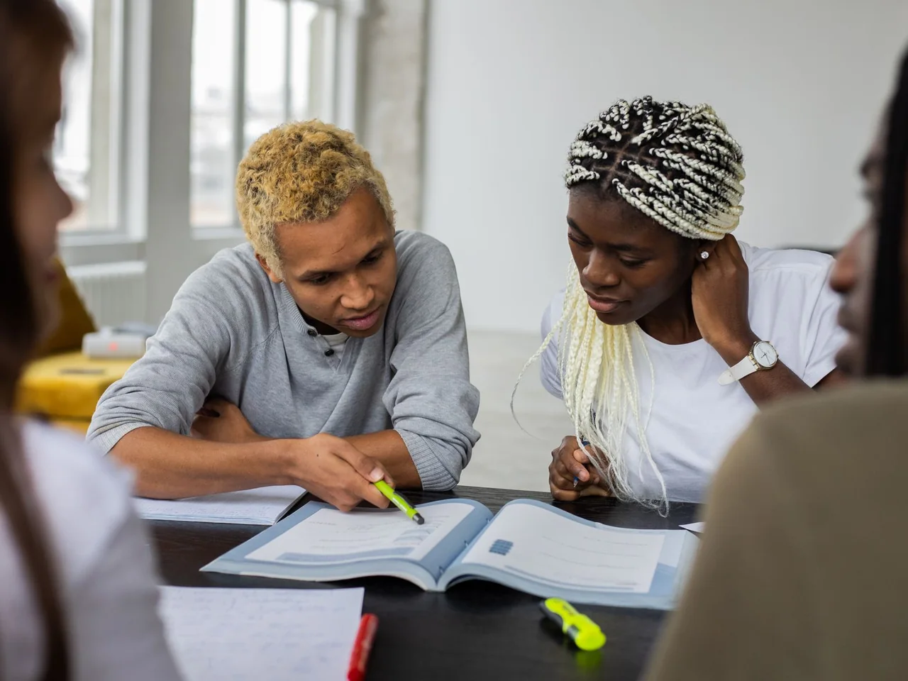 Photo by Monstera Production / Pexels — illustrative stock photo, not foundation participants Four young adults studying together around an open textbook; licensed stock photograph, not foundation participants